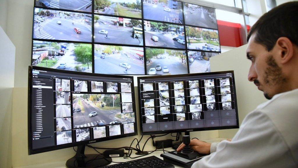Operador en una sala de monitoreo con videowall y dos monitores con mosaicos de cámaras